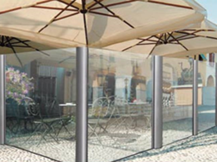 two umbrellas over tables next to glass dividers that are glass from top to bottom